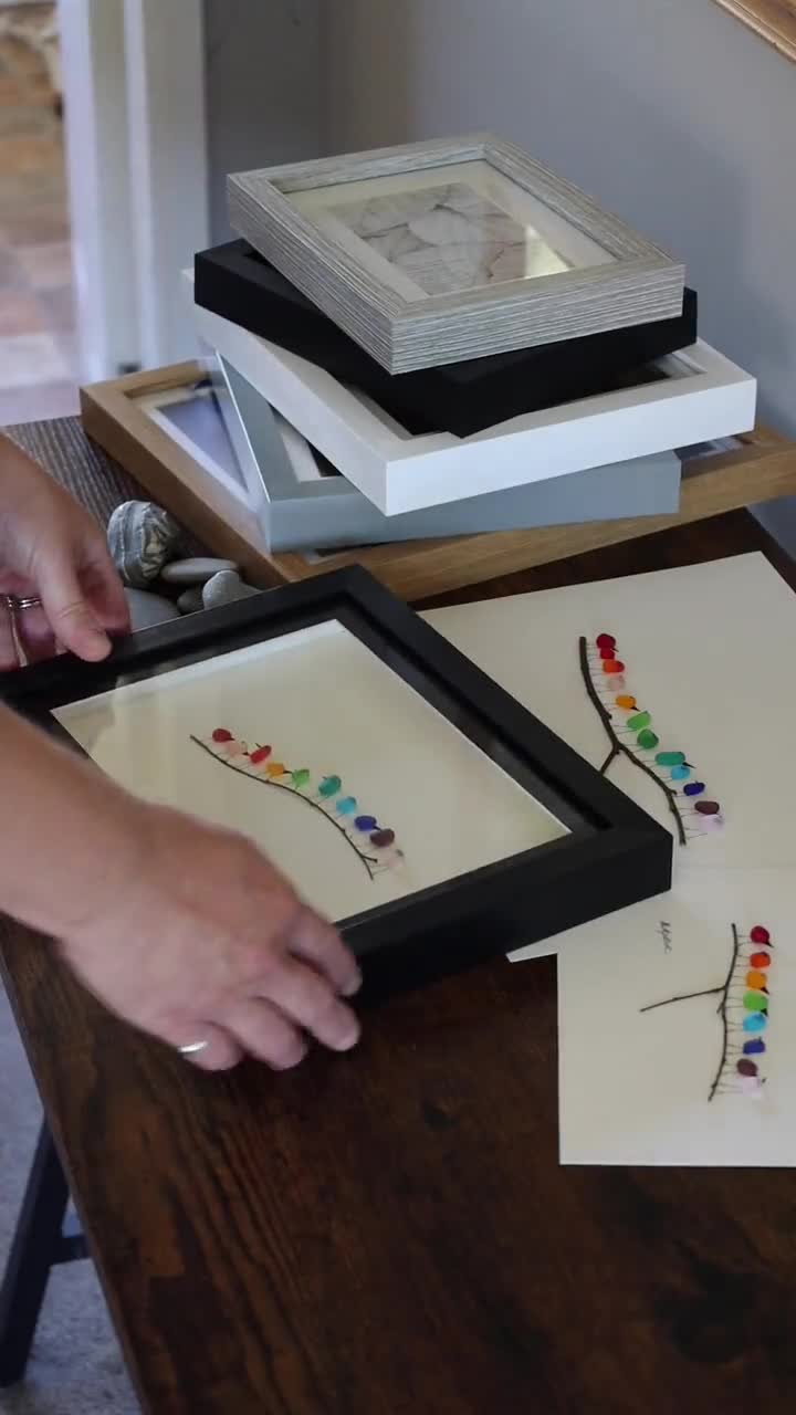 小石アートとシーグラスの絵画 - 額装された手作りの巣を作る鳥たち