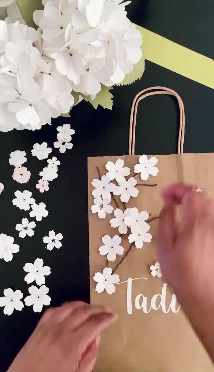 Manos de mujer envuelven regalos y flores, papel de regalo y herramientas