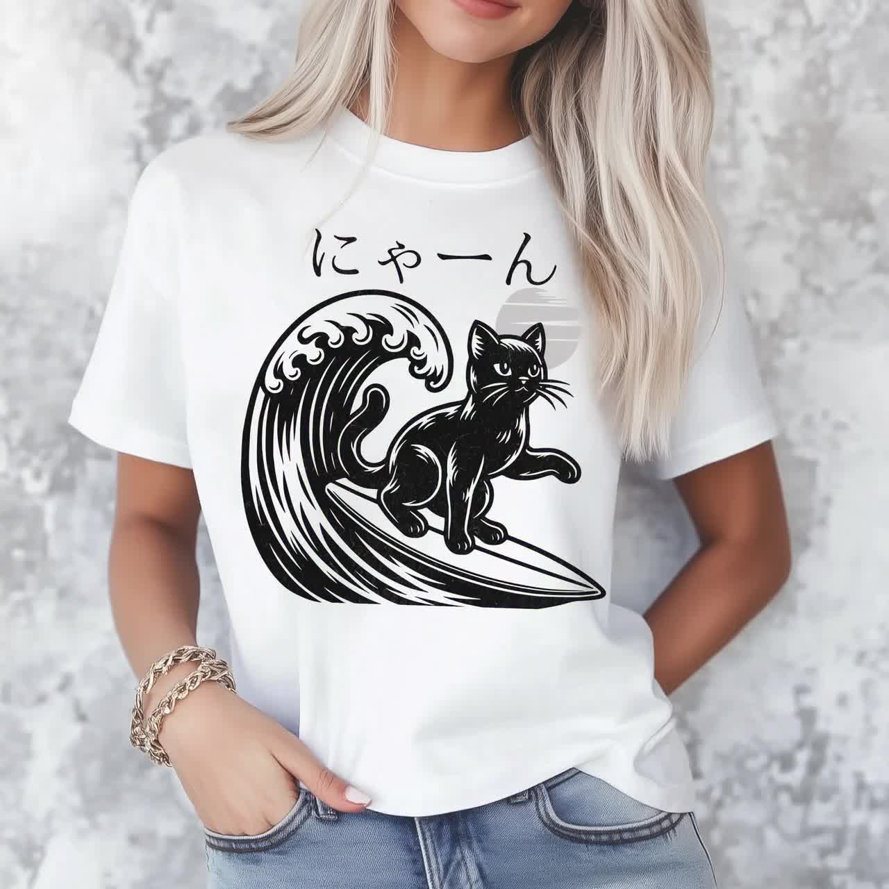 波の上でサーフィンする黒猫のグラフィックTシャツ、日本語のニャーの