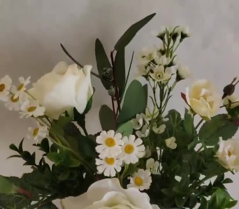 Flores artificiales en jarrones de cerámica blanca sobre la
