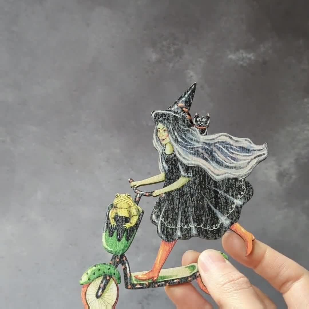 Wooden hanging ornament of a witch riding a kick scooter. Unique Halloween  decoration, retro in style. Made in the UK, image size:1080x1080