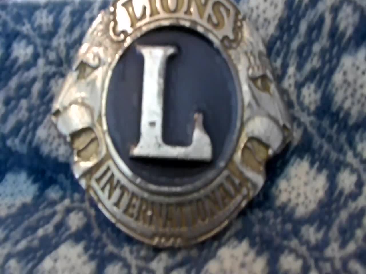 Hebilla de cinturón plateada con el logotipo de la Organización Fraternal Internacional del Club de Leones vintage video poster